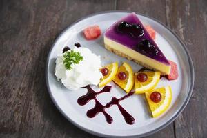 favor de mirtilo de bolo de queijo colorido com pedaços de frutas bem decorados e chantilly em chapa branca - conceito de menu de receita de bolo foto