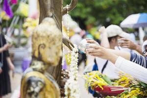 pessoas despejando água em uma imagem de buda este é um gesto de adoração - as pessoas participam do festival budista tradicional anual local de chiang mai. foto