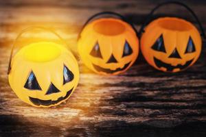 foto de tom escuro com holofotes quentes de baldes vazios de rosto de abóbora de halloween na textura de madeira velha