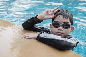 criança feliz asiática brincando na piscina foto