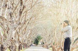 um homem está tirando foto usando a câmera dslr no caminho de caminhada da árvore de plumeria