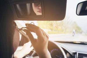 mulher maquia o rosto usando curvex enquanto dirige o carro, comportamento inseguro foto