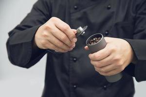 barista asiático está usando moedor de grãos de café manual para preparar café quente foto