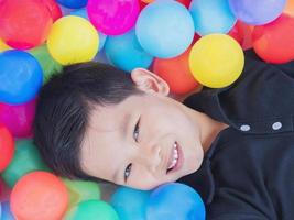 criança asiática feliz com bolas de brinquedo coloridas foto