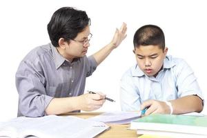 pai asiático ensinando lição de casa para seu filho de 14 anos a sério foto