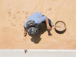 um trabalhador da construção civil está fazendo piso de lavagem de areia, trabalho ao ar livre sob luz solar forte e sombra durante o dia foto