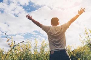 homem feliz na natureza da flor do campo amarelo e céu brilhante nuvem branca foto