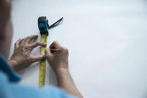 homem usando ferramenta manual de medida fazendo trabalho de corte de papel de parede no canteiro de obras, pessoas com conceito de objeto de ferramenta manual foto