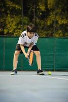 menino asiático jogando quadra de tênis durante seu tempo de prática esportiva - esporte de tênis com conceito de pessoas foto