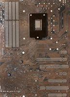 a superfície da placa-mãe, marrom escuro, tem um padrão de caminhos de dados, e a corrente tem um ponto causado por solda de chumbo. é a placa de circuito sob a CPU. foto