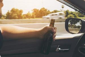 homem segurando garrafa de cerveja enquanto dirige um carro