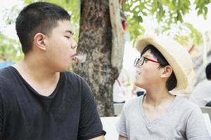 menino asiático comendo fumando canny alegremente - pessoas e lanche conceito de tempo feliz foto