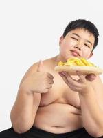 menino gordo está comendo alegremente chip. foto está focada em sua mão direita.