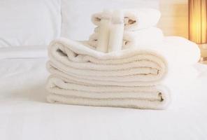 toalha de hotel com frasco de shampoo e sabonete na cama branca foto