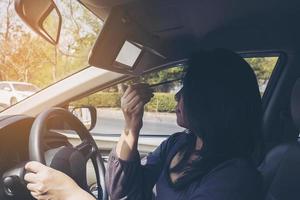 mulher maquia o rosto usando lápis de sobrancelha enquanto dirige o carro, comportamento inseguro foto