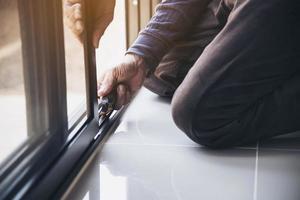 homem fazendo armação de alumínio com óculos e tela de arame trabalho de instalação de porta e janela no canteiro de obras foto