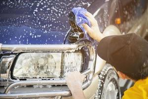 homem lavar carro usando shampoo - conceito de cuidado de carro de vida diária foto