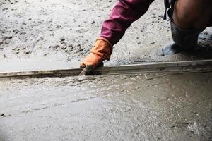 trabalhador fazendo trabalho de concretagem da superfície da estrada no canteiro de obras foto