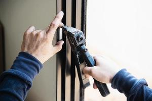 homem fazendo armação de alumínio com óculos e tela de arame trabalho de instalação de porta e janela no canteiro de obras foto