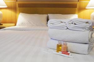 toalha de hotel com escova de dentes e creme dental na cama branca foto