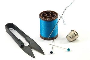 dedal, agulhas, carretéis e tesouras para costurar em um fio de fundo foto