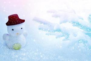 boneco de neve branco com um chapéu preto na neve. foto