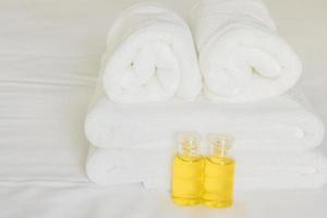 toalha de hotel com frasco de shampoo e sabonete na cama branca foto