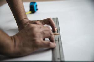 homem usando ferramenta manual de medida fazendo trabalho de corte de papel de parede no canteiro de obras, pessoas com conceito de objeto de ferramenta manual foto