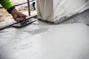 trabalhador fazendo trabalho de concretagem da superfície da estrada no canteiro de obras foto