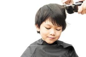 um menino é cortado o cabelo pelo cabeleireiro isolado sobre fundo branco foto