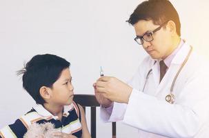 menino asiático doente sendo tratado por médico masculino foto