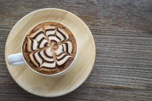 xícara de café quente vintage com decoração de arte latte agradável na velha mesa de textura de madeira foto