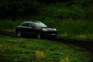 chisinau, moldávia - 17 de junho de 2021, porsche macan s em corridas off-road cheias de humor na estrada ruim na moldávia. foto editorial.