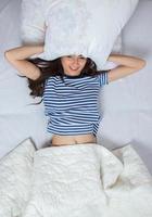 menina dorme em uma cama branca em casa. jovem dormindo em pijamas no linho branco na cama em casa, vista superior. foto