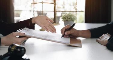 mulher de negócios e advogados discutindo papéis de contrato com escala de latão na mesa de madeira no escritório. direito, serviços jurídicos, aconselhamento, conceito de justiça. foto