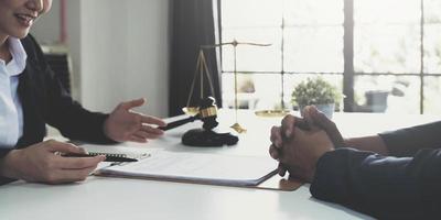 mulher de negócios e advogados discutindo papéis de contrato com escala de latão na mesa de madeira no escritório. direito, serviços jurídicos, aconselhamento, conceito de justiça. foto