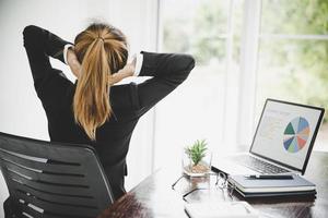 jovem mulher asiática está sentada no trabalho e tem dor no pescoço foto