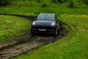 chisinau, moldávia - 17 de junho de 2021, porsche macan s em corridas off-road cheias de humor na estrada ruim na moldávia. foto editorial.