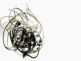 fones de ouvido e cabos de conexão ficam emaranhados. em um fundo branco, o conceito de caos. para dar uma sensação de desânimo, confusão, aborrecimento foto