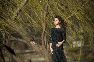 retrato de mulher com um cabelo se movendo ao vento. retrato de close-up de jovem morena russa linda no parque verde de verão. mulher branca europeia de vestido. foto