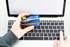 close-up de mãos femininas segurando cartão de crédito fazendo pagamento online foto