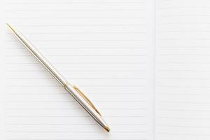 caneta e caderno aberto com página em branco foto