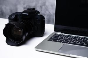 uma câmera digital preta e um laptop de computador em uma mesa. foto