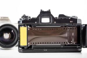 câmera reflex de lente única e um rolo de filme em um fundo branco. foto