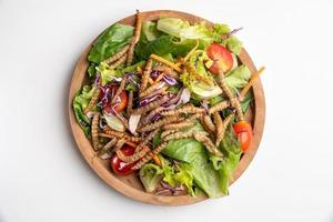 salada de legumes com lagarta de bambu frita em uma tigela de madeira. foto