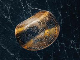 moeda de ouro torcida com símbolo bitcoin. conceito de uma crise do mercado de criptomoedas. foto