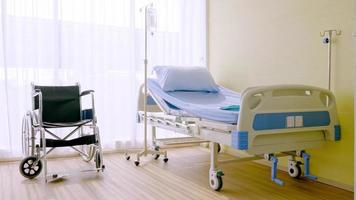 cama de hospital e cadeira de rodas no quarto de hospital. foto