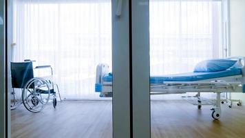 quarto para paciente em um hospital, cama vazia e cadeira de rodas na enfermaria do hospital. foto