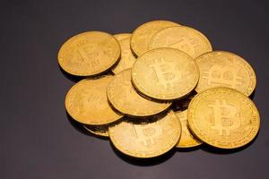 moedas de ouro com símbolo bitcoin em um fundo preto. foto