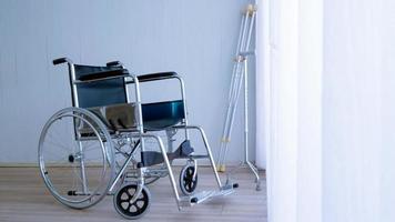 cadeira de rodas moderna vazia e bengala ou bengalas no quarto do hospital. foto